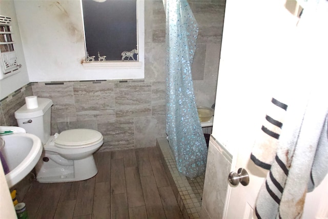 10406 Broadstairs St, Houston, TX 77013 - full bathroom featuring tile walls, toilet, a tile shower, wood finished floors, and a wainscoted wall