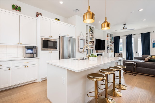 1747 Ojeman Spring Ln, Houston, TX 77055 - kitchen featuring stainless steel appliances, open floor plan, light wood-style floors, recessed lighting, and white cabinetry
