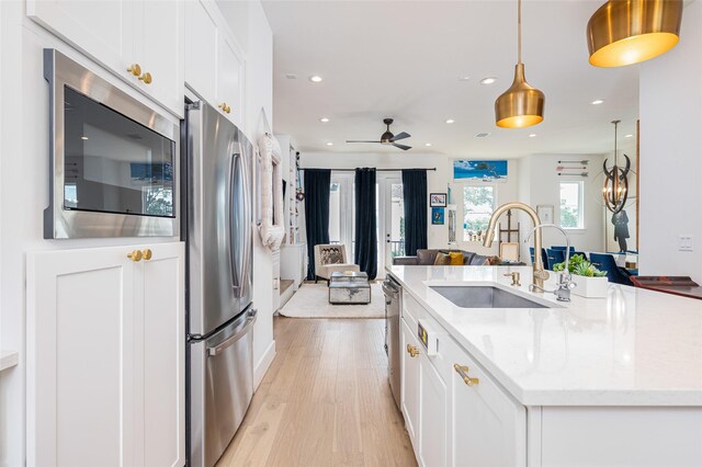 1747 Ojeman Spring Ln, Houston, TX 77055 - kitchen with stainless steel appliances, recessed lighting, white cabinetry, open floor plan, and light wood-style flooring
