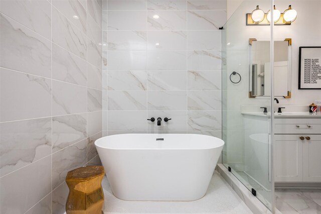 1747 Ojeman Spring Ln, Houston, TX 77055 - bathroom featuring double vanity, a soaking tub, marble look tile flooring, and tile walls