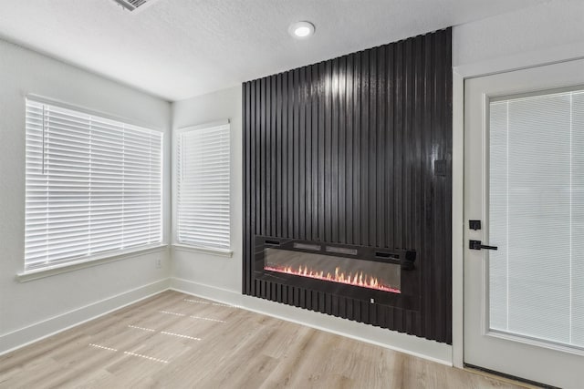 16739 Innisbrook Dr, Houston, TX 77095 - detailed view of a glass covered fireplace, wood finished floors, baseboards, a textured ceiling, and recessed lighting