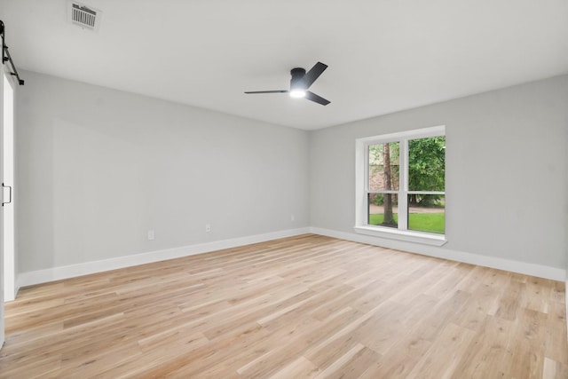 9 Indian Cedar Ln, The Woodlands, TX 77380 - unfurnished room featuring a barn door, a ceiling fan, light wood-style flooring, and baseboards