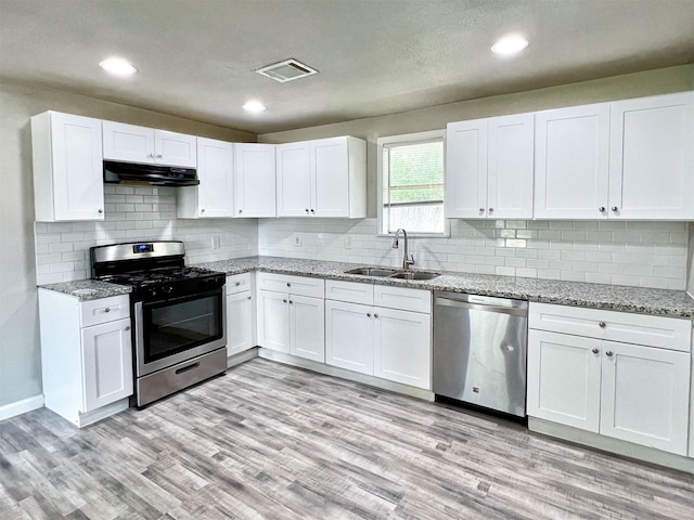 5813 Mayle St, Houston, TX 77016 - kitchen with stainless steel appliances, a sink, under cabinet range hood, white cabinetry, and recessed lighting