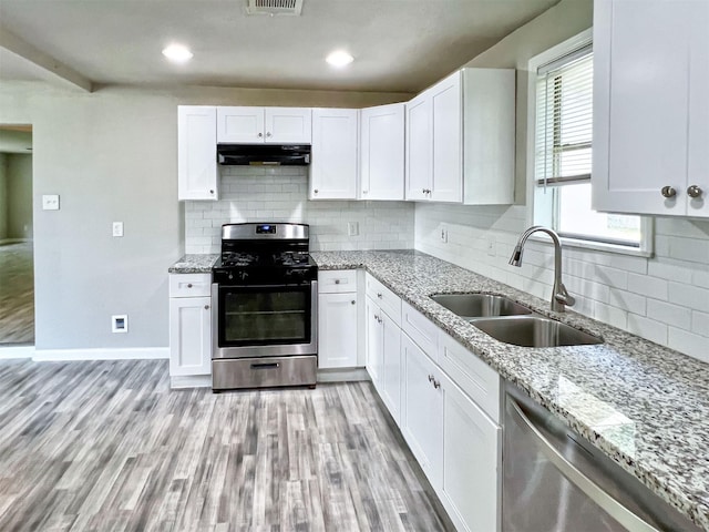 5813 Mayle St, Houston, TX 77016 - kitchen featuring stainless steel appliances, a sink, under cabinet range hood, tasteful backsplash, and light stone counters