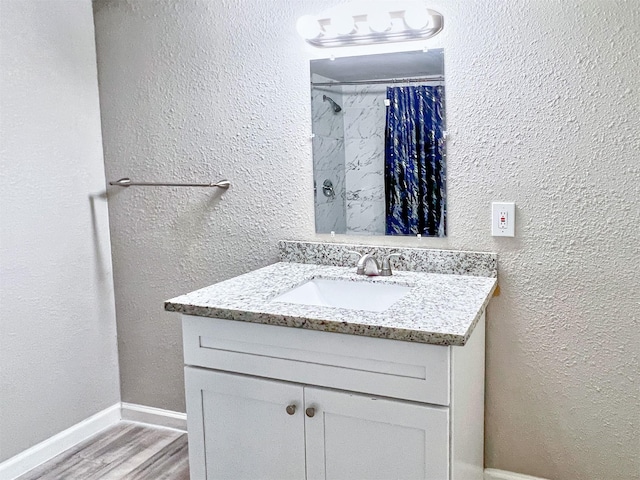 5813 Mayle St, Houston, TX 77016 - full bath with vanity, wood finished floors, a shower with curtain, a textured wall, and baseboards