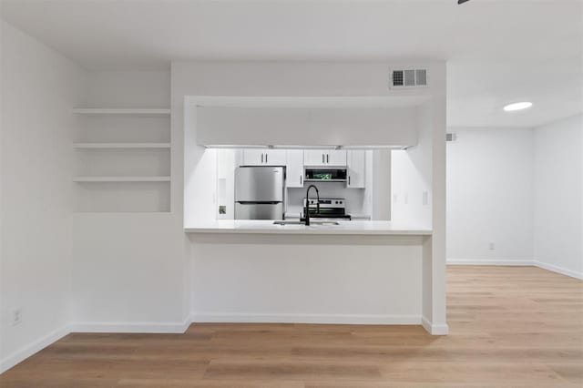 815 Lyle W Ave Unit A, Cleveland, TX 77327 - kitchen with appliances with stainless steel finishes, white cabinetry, light countertops, light wood-style floors, and a peninsula