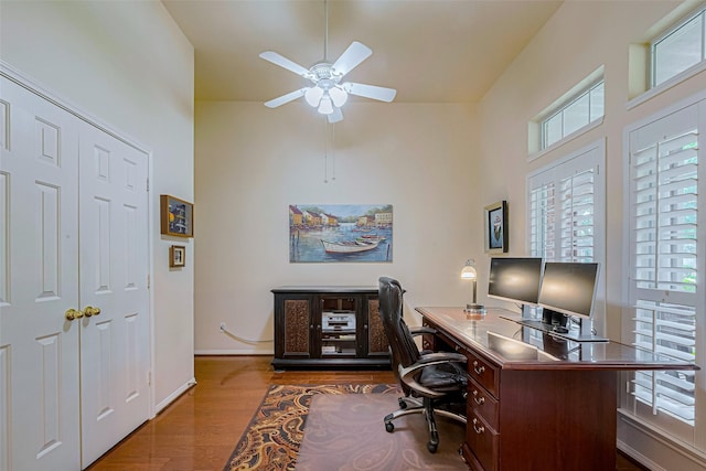 13719 Highland Cove Dr, Houston, TX 77070 - home office featuring a towering ceiling, a ceiling fan, dark wood finished floors, and baseboards