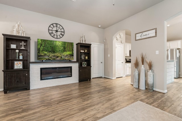 1724 Wandering Hills Rd, Conroe, TX 77304 - unfurnished living room with wood finished floors, baseboards, arched walkways, and a fireplace