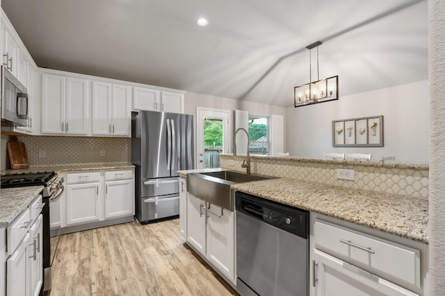 1724 Wandering Hills Rd, Conroe, TX 77304 - kitchen featuring stainless steel appliances, a sink, tasteful backsplash, light wood-style flooring, and white cabinetry
