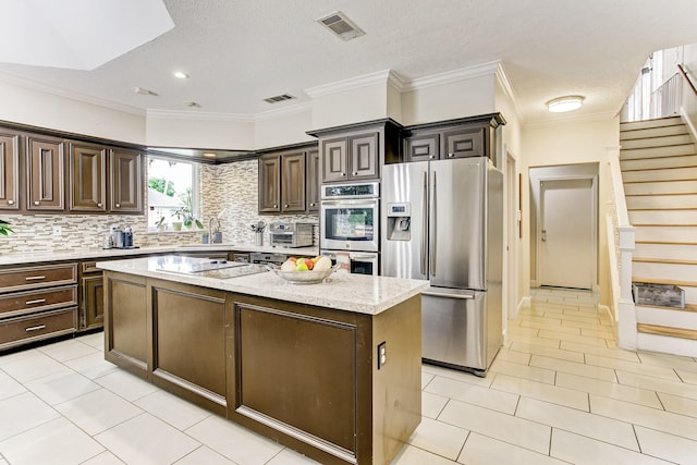 12203 Maple Rock Dr, Houston, TX 77077 - kitchen featuring stainless steel appliances, a kitchen island, tasteful backsplash, dark brown cabinets, and crown molding