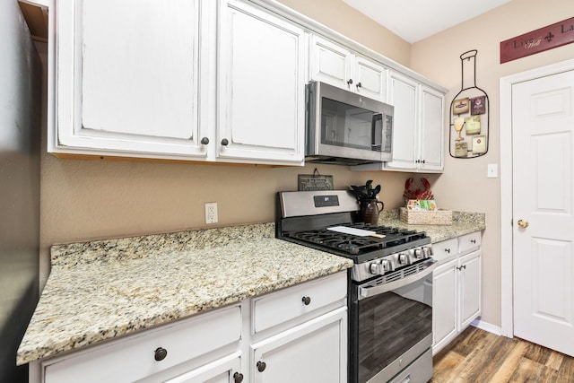 259 Adobe Ter S, Conroe, TX 77316 - kitchen with stainless steel appliances, wood finished floors, white cabinets, and light stone counters
