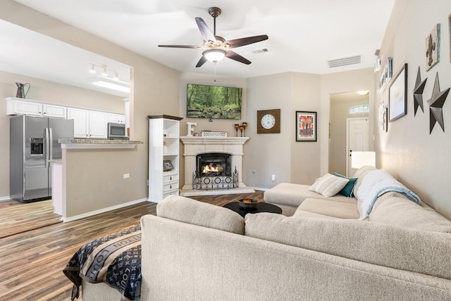 259 Adobe Ter S, Conroe, TX 77316 - living area featuring wood finished floors, ceiling fan, baseboards, and a warm lit fireplace
