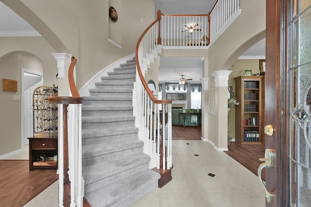 17419 Crescent Canyon Dr, Houston, TX 77095 - tiled entryway featuring arched walkways, a ceiling fan, ornamental molding, stairs, and decorative columns