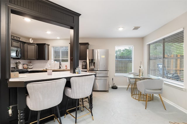 5227 Aberton Ln, Spring, TX 77379 - kitchen featuring appliances with stainless steel finishes, baseboards, a breakfast bar area, light countertops, and dark brown cabinetry