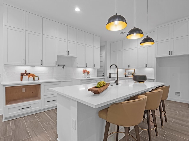 852 Rd 6609, Dayton, TX 77535 - kitchen with tasteful backsplash, a breakfast bar, an island with sink, white cabinets, and pendant lighting