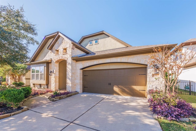 11 Floral Hills Ln, Fulshear, TX 77441 - view of front of house featuring stone siding, an attached garage, and driveway