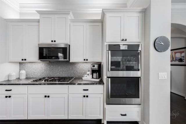 11 Floral Hills Ln, Fulshear, TX 77441 - kitchen featuring appliances with stainless steel finishes, white cabinetry, crown molding, tasteful backsplash, and dark stone counters