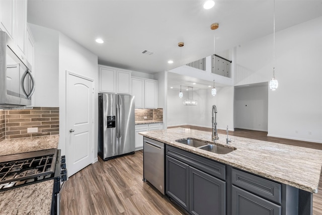 18202 Fehmarn Sound Cir, Houston, TX 77044 - kitchen featuring appliances with stainless steel finishes, a sink, white cabinets, backsplash, and light stone counters