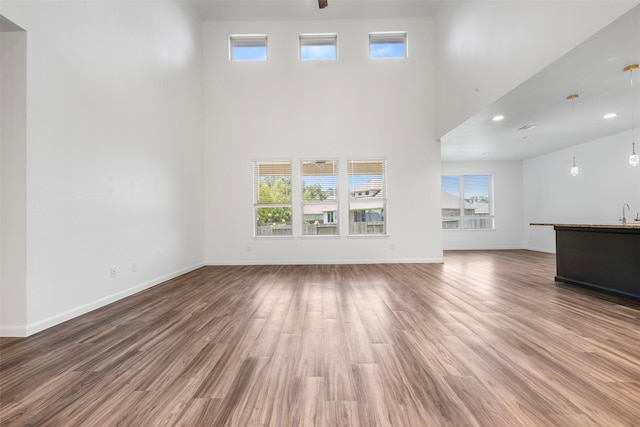 18202 Fehmarn Sound Cir, Houston, TX 77044 - unfurnished living room with a towering ceiling, wood finished floors, baseboards, and recessed lighting