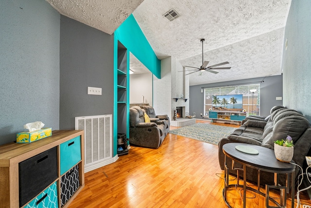 327 Brompton Ct, Highlands, TX 77562 - living area featuring a ceiling fan, wood finished floors, a fireplace, a textured ceiling, and vaulted ceiling