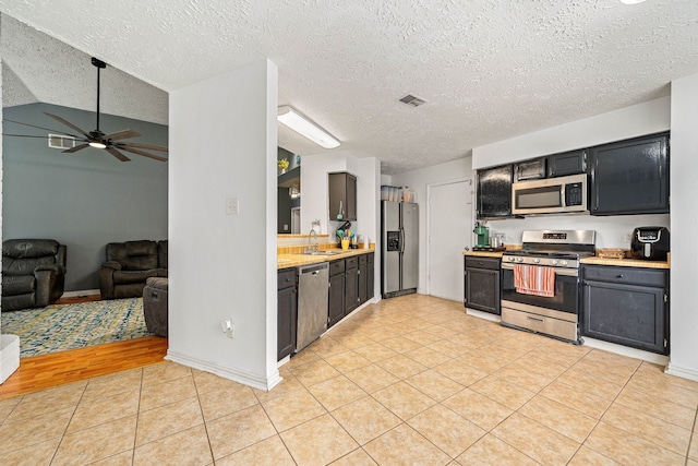 327 Brompton Ct, Highlands, TX 77562 - kitchen with appliances with stainless steel finishes, a sink, light countertops, light tile patterned floors, and a ceiling fan