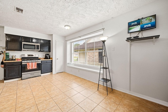 327 Brompton Ct, Highlands, TX 77562 - kitchen with stainless steel appliances, a textured ceiling, light countertops, light tile patterned floors, and baseboards
