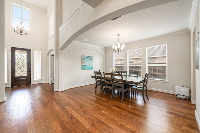 300 Bentside Pl, Clute, TX 77531 - dining space with a chandelier, arched walkways, dark wood finished floors, crown molding, and baseboards