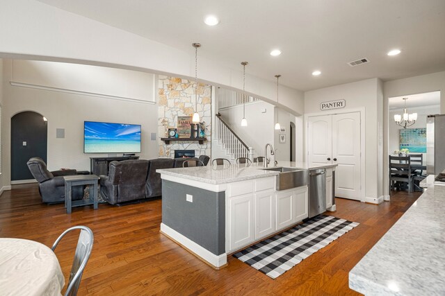 300 Bentside Pl, Clute, TX 77531 - kitchen with arched walkways, stainless steel dishwasher, white cabinets, a sink, and a chandelier