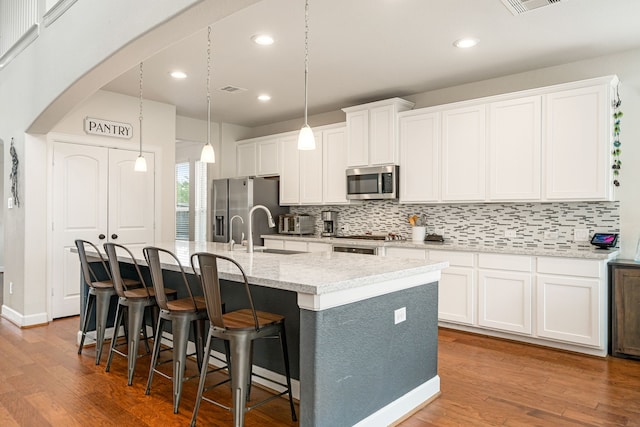 300 Bentside Pl, Clute, TX 77531 - kitchen with stainless steel appliances, a kitchen island with sink, a sink, backsplash, and white cabinetry