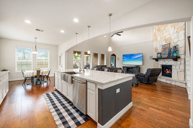 300 Bentside Pl, Clute, TX 77531 - kitchen with dishwasher, a sink, a stone fireplace, dark wood-type flooring, and white cabinetry
