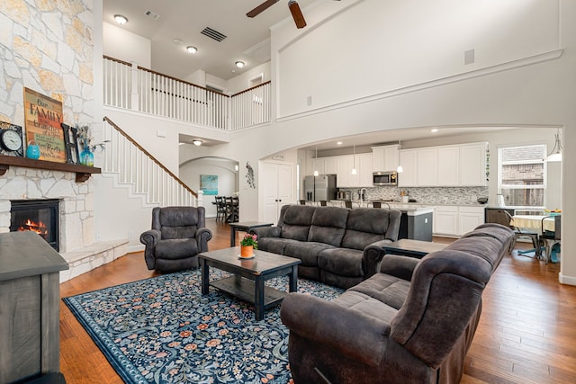 300 Bentside Pl, Clute, TX 77531 - living room with arched walkways, a stone fireplace, ceiling fan, hardwood / wood-style flooring, and a towering ceiling