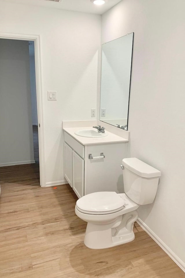 318 Riverwood Village Ln, Sealy, TX 77474 - half bathroom featuring toilet, vanity, wood finished floors, and baseboards