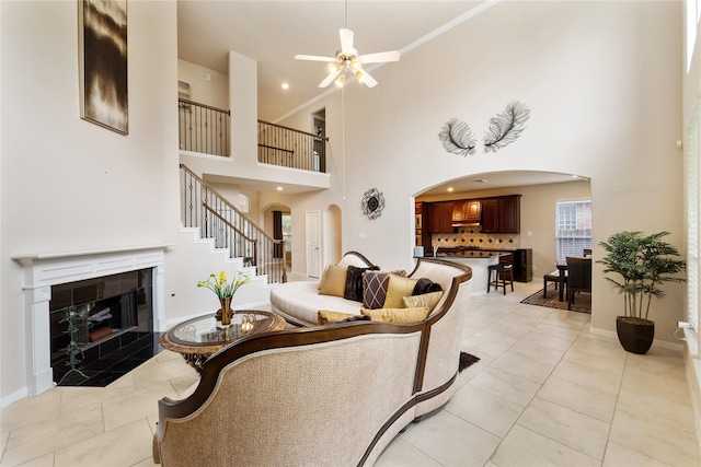 4610 Countrymeadows Dr, Spring, TX 77388 - living room with arched walkways, ceiling fan, a high ceiling, a tile fireplace, and light tile patterned flooring