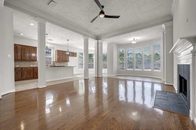 3935 Waverly Bnd, Katy, TX 77450 - unfurnished living room featuring ceiling fan, light wood-style flooring, a textured ceiling, crown molding, and a fireplace with flush hearth