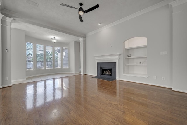 3935 Waverly Bnd, Katy, TX 77450 - unfurnished living room featuring built in shelves, ceiling fan, wood finished floors, baseboards, and ornamental molding