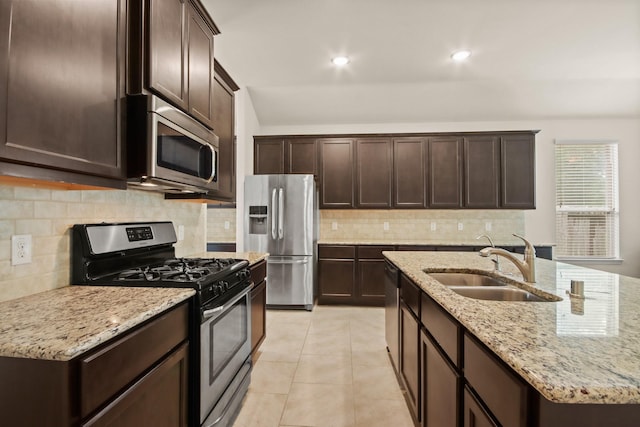 14021 Buffalo Gap Trl, Conroe, TX 77384 - kitchen featuring stainless steel appliances, a sink, dark brown cabinets, tasteful backsplash, and light stone countertops