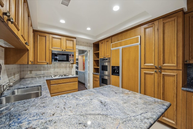 2628 Glen Haven Blvd, Houston, TX 77025 - kitchen featuring black microwave, paneled built in fridge, double oven, brown cabinets, and light stone counters