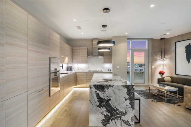 4521 San Felipe St Unit 1201, Houston, TX 77027 - kitchen with modern cabinets, wall chimney range hood, light wood-style flooring, a sink, and oven