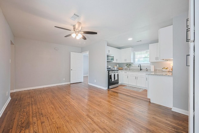 2218 Silverbonnet St, Houston, TX 77055 - kitchen with stainless steel appliances, ceiling fan, white cabinets, light wood-type flooring, and recessed lighting