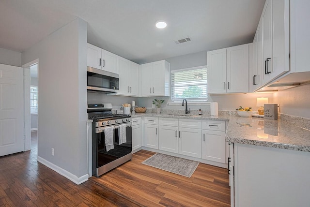 2218 Silverbonnet St, Houston, TX 77055 - kitchen featuring appliances with stainless steel finishes, wood finished floors, light stone countertops, and white cabinetry