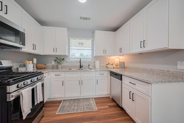 2218 Silverbonnet St, Houston, TX 77055 - kitchen with stainless steel appliances, white cabinetry, wood finished floors, and light stone countertops