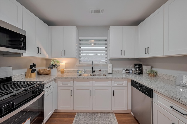 2218 Silverbonnet St, Houston, TX 77055 - kitchen with appliances with stainless steel finishes, white cabinetry, dark wood-style flooring, and light stone counters