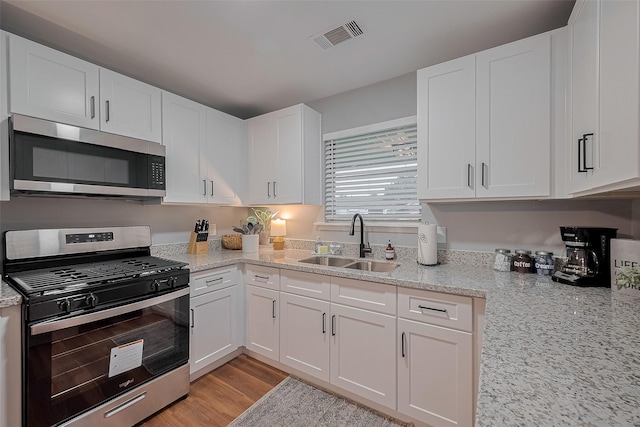 2218 Silverbonnet St, Houston, TX 77055 - kitchen with stainless steel appliances, white cabinetry, light stone countertops, and light wood-style floors