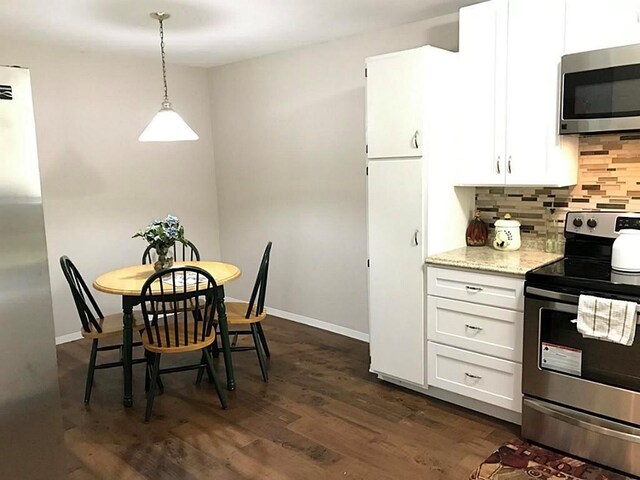 5734 Arthington St, Houston, TX 77053 - kitchen with stainless steel appliances, decorative backsplash, white cabinets, light stone counters, and pendant lighting