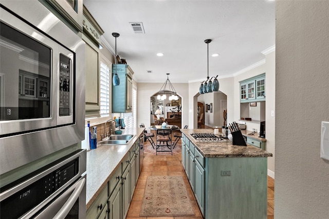 926 Grand Oaks Cir, College Station, TX 77840 - kitchen with a sink, stainless steel appliances, ornamental molding, arched walkways, and hanging light fixtures