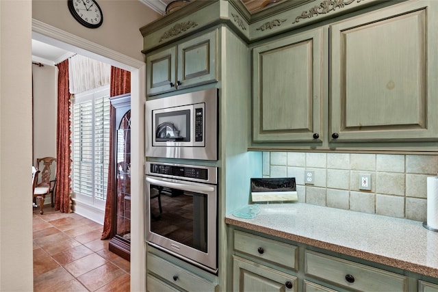 926 Grand Oaks Cir, College Station, TX 77840 - kitchen with stainless steel appliances, crown molding, decorative backsplash, light tile patterned floors, and light stone counters
