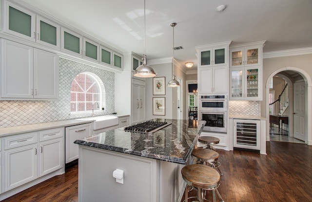 4516 Palmetto St, Bellaire, TX 77401 - kitchen with beverage cooler, appliances with stainless steel finishes, arched walkways, a sink, and ornamental molding