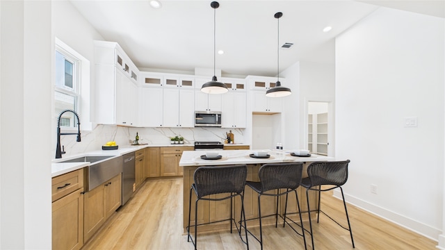 1637 Beall St, Houston, TX 77008 - kitchen featuring stainless steel appliances, backsplash, light wood finished floors, a kitchen island, and glass insert cabinets