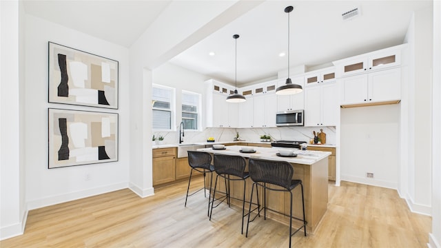 1637 Beall St, Houston, TX 77008 - kitchen featuring appliances with stainless steel finishes, light wood-type flooring, backsplash, light countertops, and a breakfast bar area