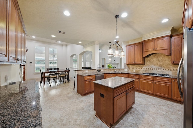 3602 Lindhaven Dr, Pearland, TX 77584 - kitchen featuring a sink, brown cabinetry, a peninsula, stainless steel appliances, and arched walkways